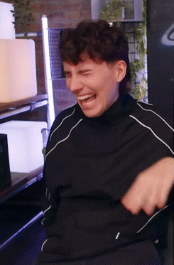 A Man Wearing A Black Shirt Is Laughing With His Mouth Open GIF