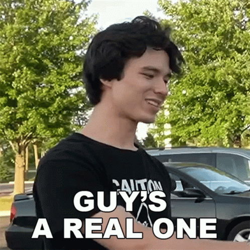 A Man Wearing A Black Shirt That Says Caution Guy 'S A Real One On It GIF