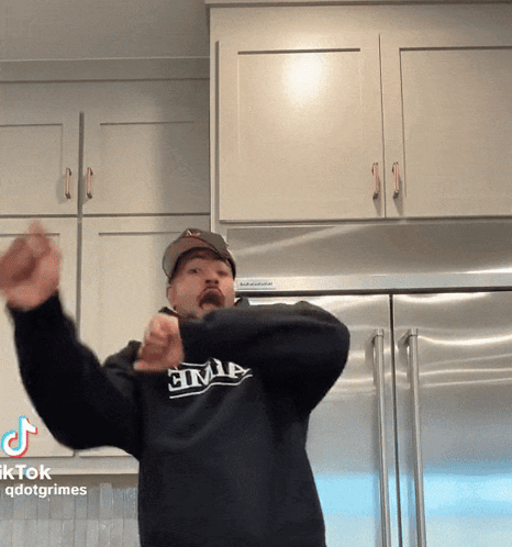 A Man Wearing A Black Shirt That Says Civil Is Standing In Front Of A Refrigerator GIF