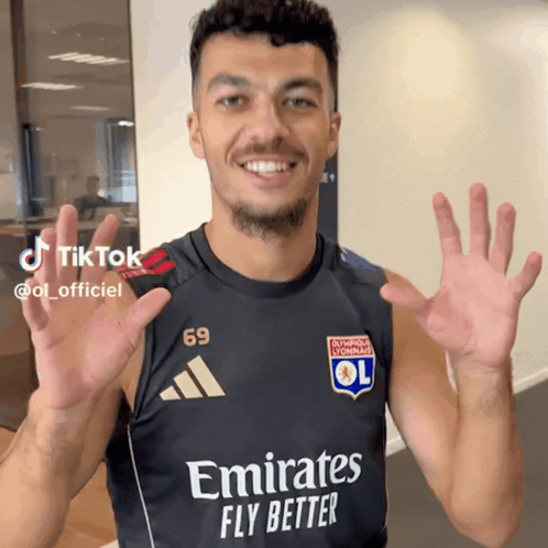 A Man Wearing A Black Shirt That Says Emirates Fly Better On It GIF