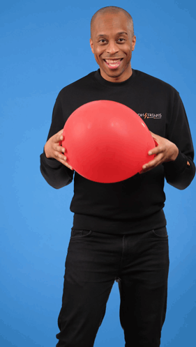 A Man Wearing A Black Shirt That Says Ghostbusters Holds A Red Balloon In His Hands GIF