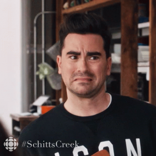 A Man Wearing A Black Shirt That Says Schitts Creek On It GIF