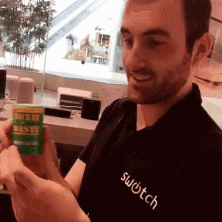 A Man Wearing A Black Shirt That Says Switch Holds A Green Bottle GIF