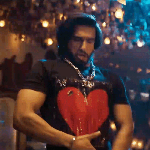 A Man Wearing A Black Shirt With A Heart On It GIF