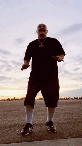 A Man Wearing A Black Shirt With A Pendant That Says ' Reggae ' On It GIF