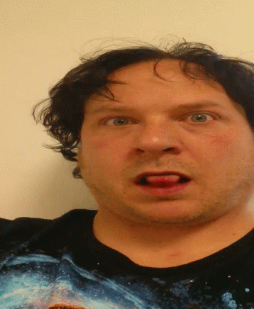 A Man Wearing A Black Shirt With A Picture Of A Shark On It Is Making A Funny Face GIF