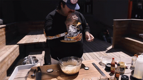 A Man Wearing A Black Shirt With An Eagle On It Is Cooking GIF