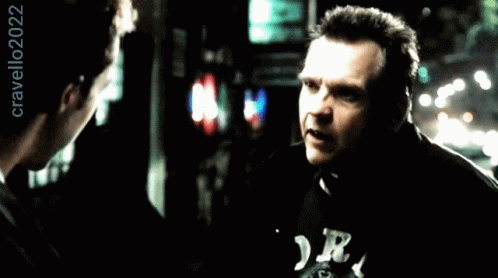 A Man Wearing A Black Shirt With The Letter R On It Talks To Another Man GIF