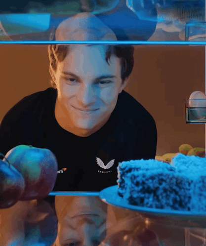 A Man Wearing A Black Shirt With The Letter V On It Looks At A Cake GIF