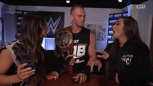 a man wearing a black shirt with the number 18 on it is surrounded by two women