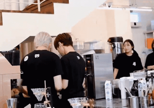 a man wearing a black shirt with the number 5 on it is standing in a kitchen