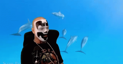 A Man Wearing A Black Shirt With The Word Six On It Stands In Front Of Dolphins GIF