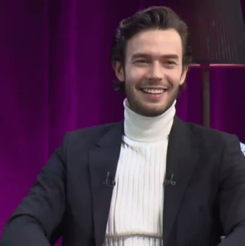 a man wearing a black suit and a white turtleneck sweater