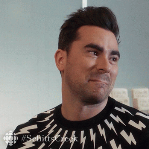 A Man Wearing A Black Sweater With Lightning Bolts On It Is Smiling GIF