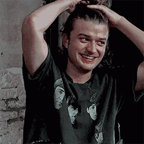 A Man Wearing A Black T-Shirt With Three Faces On It Is Smiling . GIF