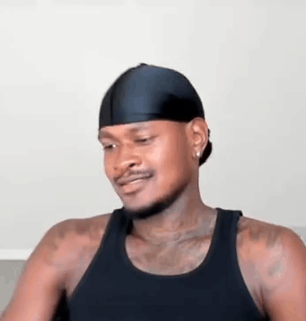 A Man Wearing A Black Tank Top And A Black Headband Is Sitting On A Couch . GIF