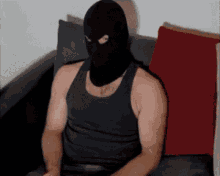 A Man Wearing A Black Tank Top And A Black Mask Is Sitting On A Couch GIF