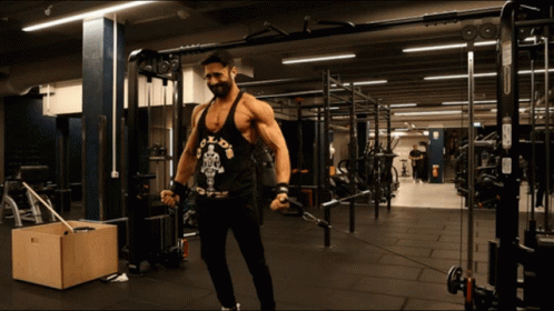 A Man Wearing A Black Tank Top That Says Gold 'S Gym GIF