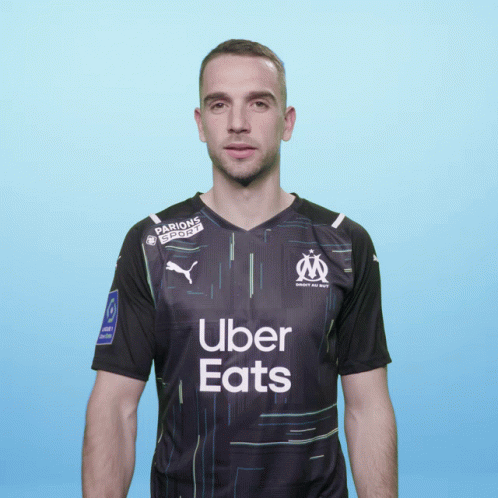 A Man Wearing A Black Uber Eats Shirt Stands In Front Of A Blue Background GIF