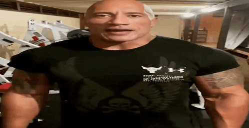 A Man Wearing A Black Under Armour Shirt Is Standing In A Gym GIF