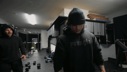 A Man Wearing A Black Youngla Hoodie Stands In A Gym GIF