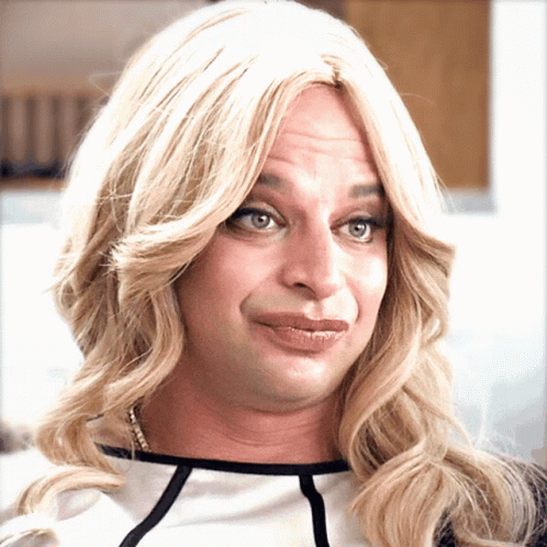 A Man Wearing A Blonde Wig And A Black And White Shirt Makes A Funny Face GIF