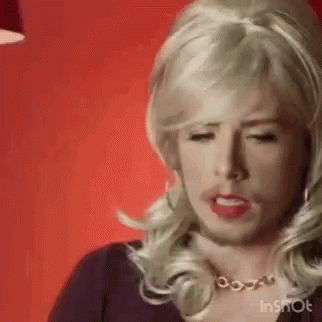 A Man Wearing A Blonde Wig And A Necklace Is Making A Face . GIF