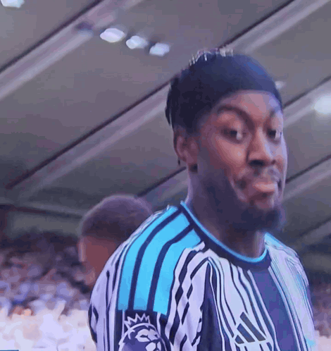 a man wearing a blue and white adidas shirt looks at the camera