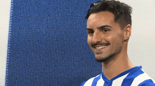 A Man Wearing A Blue And White Striped Shirt Smiles For The Camera GIF