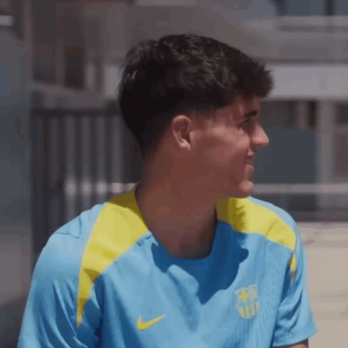 a man wearing a blue and yellow nike shirt looks to the side