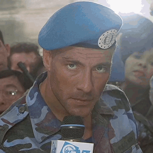 A Man Wearing A Blue Beret Is Holding A Microphone With A Box That Says Cnn On It GIF
