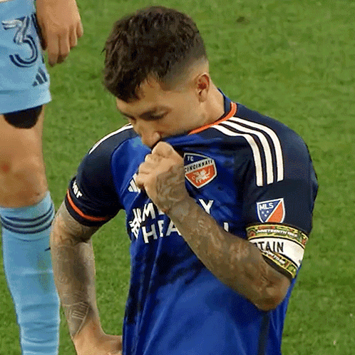 A Man Wearing A Blue Cincinnati Fc Jersey Holds His Shirt Up To His Face GIF