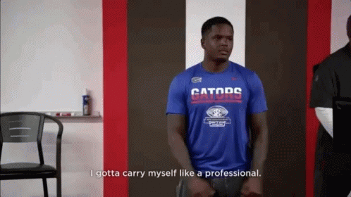 a man wearing a blue gators shirt is standing in a room .