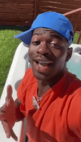 A Man Wearing A Blue Hat And A Red Shirt Is Standing Next To A Hot Tub GIF