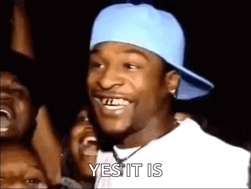A Man Wearing A Blue Hat And A White Shirt Is Smiling In Front Of A Crowd Of People . GIF