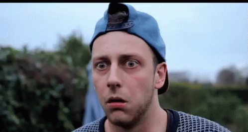 A Man Wearing A Blue Hat And Sweater Is Making A Surprised Face . GIF