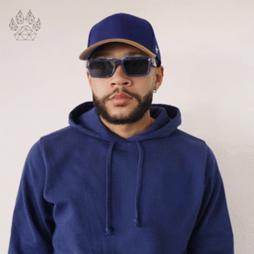 a man wearing a blue hoodie and sunglasses stands in front of a paw print