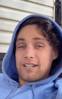 A Man Wearing A Blue Hoodie Is Smiling For The Camera GIF