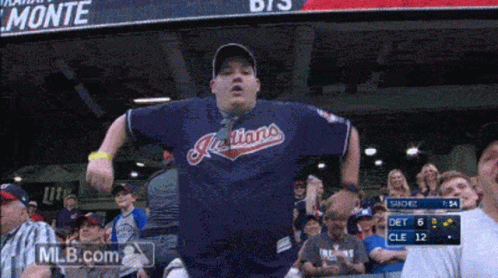A Man Wearing A Blue Indians Jersey Stands In The Stands GIF