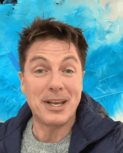 A Man Wearing A Blue Jacket And A Grey Sweater Is Smiling GIF