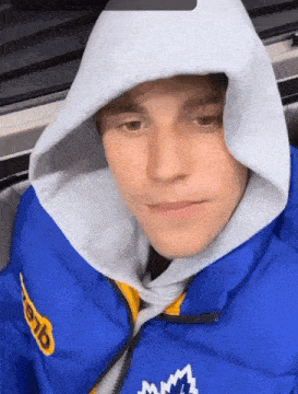 A Man Wearing A Blue Jacket And A White Hoodie With The Word Mlb On It GIF