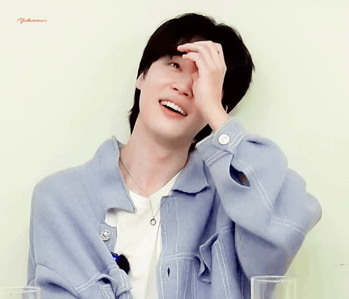 A Man Wearing A Blue Jacket And A White Shirt Is Smiling And Covering His Face With His Hand GIF