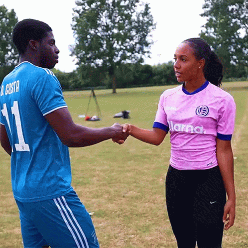 a man wearing a blue jersey with the number 11 shakes hands with a woman wearing a pink shirt