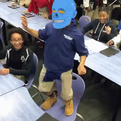 A Man Wearing A Blue Mask Is Dancing In Front Of A Group Of Children GIF