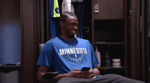A Man Wearing A Blue Minnesota Basketball Shirt Looks At His Phone GIF