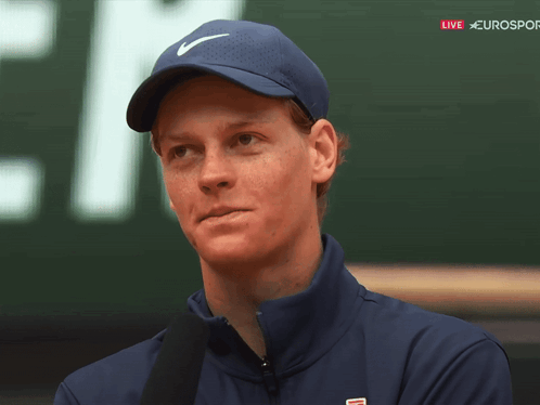 A Man Wearing A Blue Nike Hat Stands In Front Of A Sign That Says Eurosport GIF