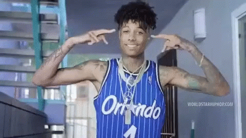 a man wearing a blue orlando jersey is smiling and pointing at his ears .