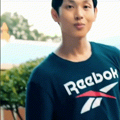 A Man Wearing A Blue Reebok Shirt Stands In Front Of Trees GIF