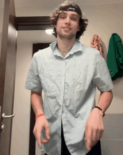 A Man Wearing A Blue Shirt And A Black Hat With A S On It GIF
