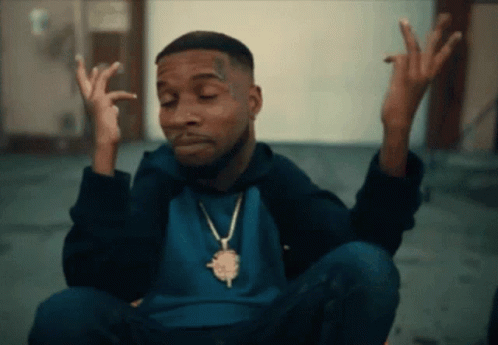 A Man Wearing A Blue Shirt And A Gold Necklace Is Making A Face GIF